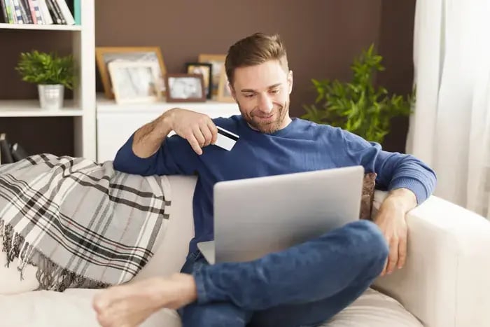 homme-souriant-lors-des-achats-en-ligne-a-la-maison