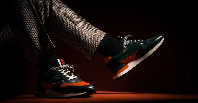 Uomo che indossa sneaker nuove su sfondo scuro.